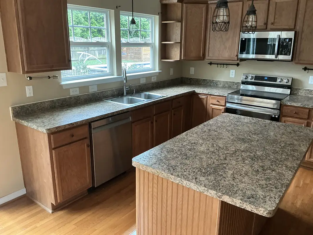 Kitchen before countertop replacement, with speckled countertops and a matching island.